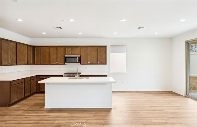 4180 Larchwood Ln, Lake Elsinore, CA 92530 - kitchen with stainless steel microwave, light countertops, a kitchen island with sink, light wood-style flooring, and recessed lighting