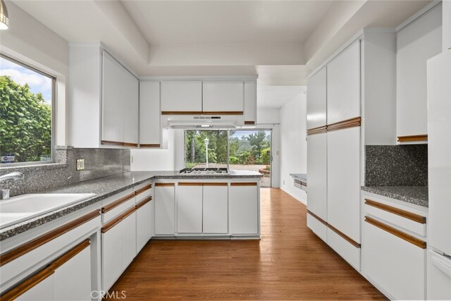 10835 Savona Rd, Los Angeles, CA 90077 - kitchen featuring under cabinet range hood, white cabinets, decorative backsplash, and a peninsula
