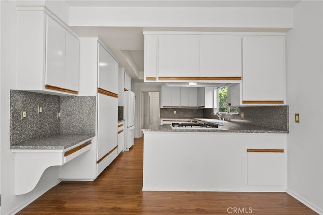 10835 Savona Rd, Los Angeles, CA 90077 - kitchen with freestanding refrigerator, white cabinetry, a peninsula, dark wood-style floors, and tasteful backsplash