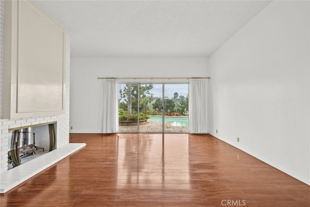 10835 Savona Rd, Los Angeles, CA 90077 - unfurnished living room featuring wood finished floors, a brick fireplace, and a textured ceiling