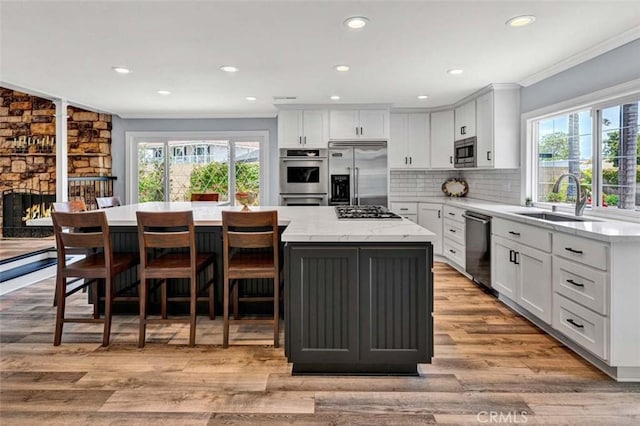 21772 Windsong Cir, Huntington Beach, CA 92646 - kitchen with appliances with stainless steel finishes, a sink, ornamental molding, a center island, and white cabinets