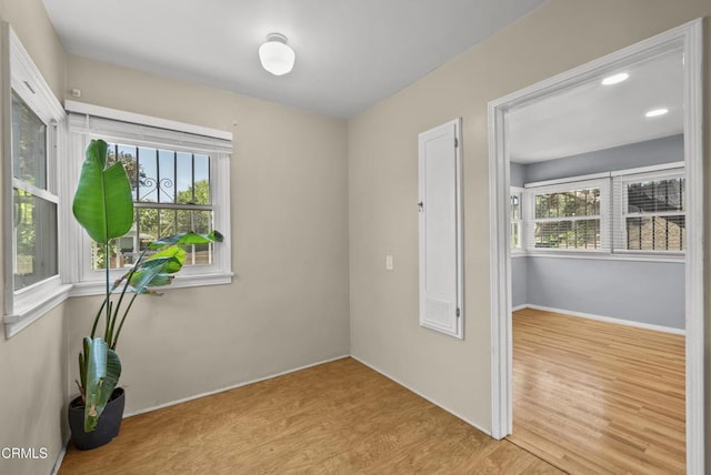 spare room featuring wood finished floors, plenty of natural light, and baseboards