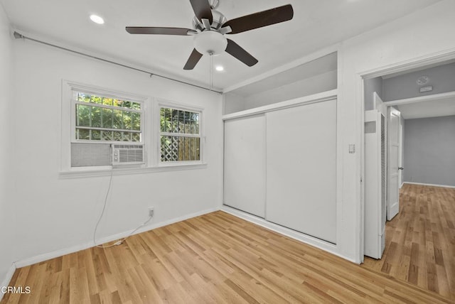 unfurnished bedroom with light wood finished floors, a closet, cooling unit, a heating unit, and baseboards