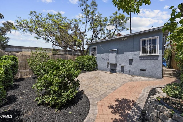view of side of property featuring stucco siding and a patio area