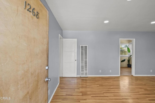 spare room with a heating unit, wood finished floors, baseboards, and recessed lighting