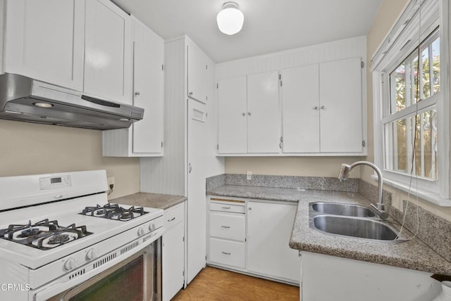 kitchen featuring gas range gas stove, under cabinet range hood, a sink, white cabinetry, and light countertops