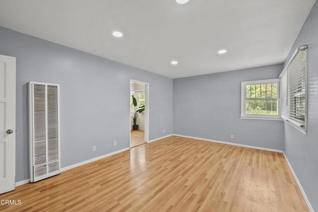 unfurnished room featuring a heating unit, plenty of natural light, wood finished floors, and recessed lighting