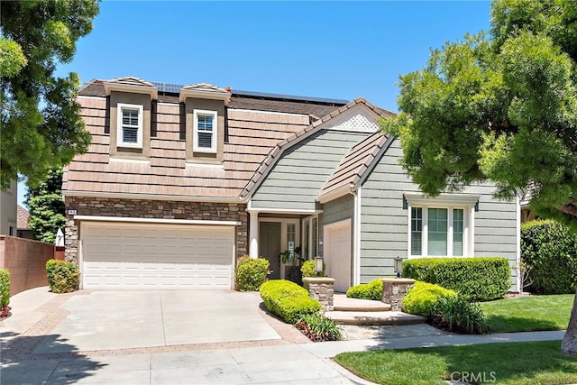 43 Flintridge, Ladera Ranch, CA 92694 - view of front of property with driveway, roof mounted solar panels, a garage, a tile roof, and stone siding