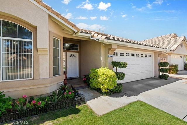 4856 W Glen Abbey Way, Banning, CA 92220 - property entrance featuring stucco siding, a garage, a tiled roof, and driveway