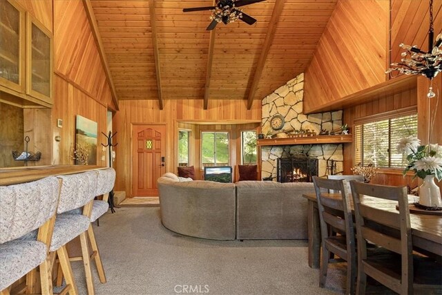 267 Pioneer Rd, Lake Arrowhead, CA 92317 - carpeted living room with wood ceiling with exposed beams, a stone fireplace, wood walls, a ceiling fan, and high vaulted ceiling
