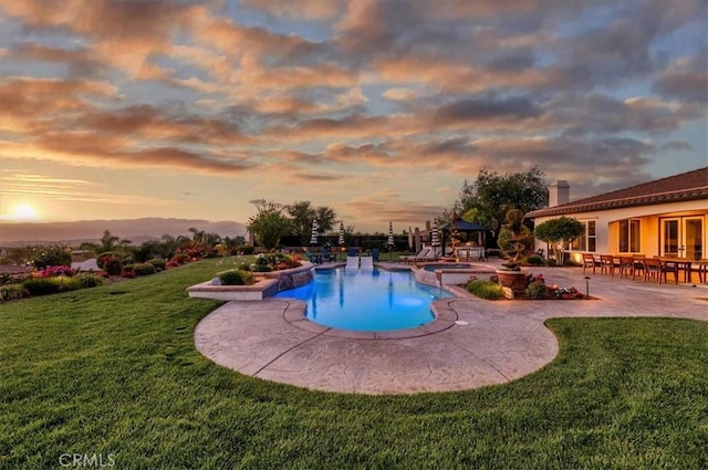 pool at dusk with a patio, a lawn, a gazebo, and a pool with connected hot tub
