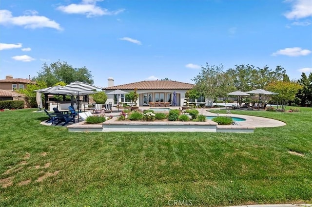 rear view of property with a chimney, a tile roof, a patio, and a yard