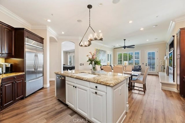kitchen with stainless steel appliances, a sink, a ceiling fan, light wood-style floors, and open floor plan