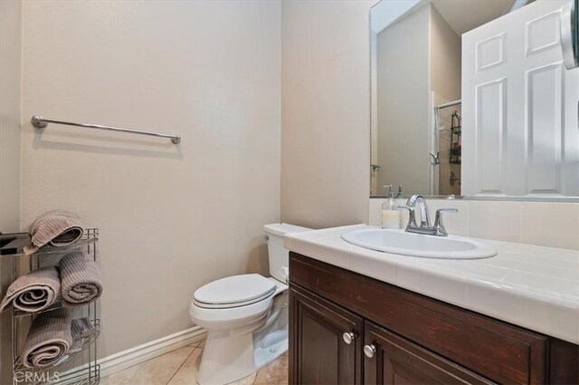 bathroom featuring a shower stall, toilet, tile patterned flooring, vanity, and baseboards