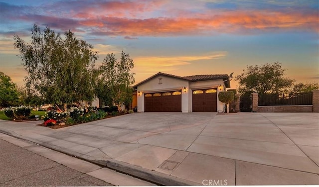 mediterranean / spanish-style home with an attached garage, driveway, stucco siding, and a tiled roof