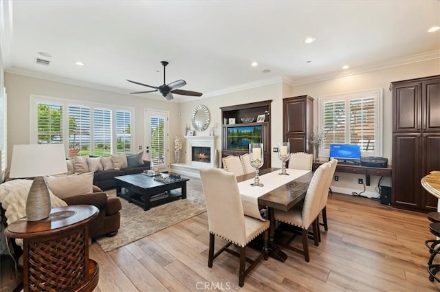 dining space featuring ceiling fan, a lit fireplace, light wood-type flooring, plenty of natural light, and recessed lighting