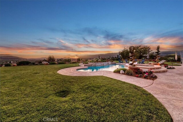 pool at dusk with a yard and an outdoor pool