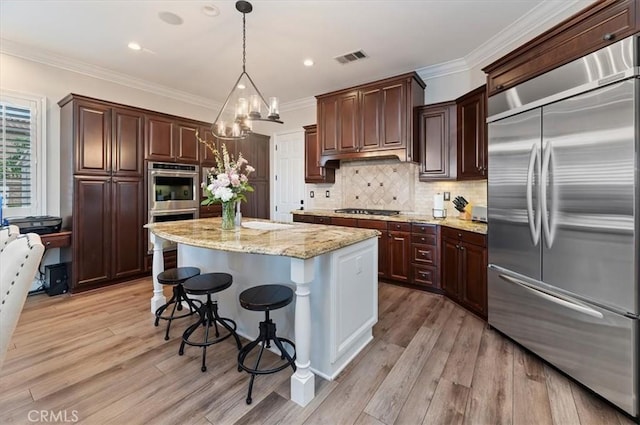 kitchen with stainless steel appliances, a center island, light wood-type flooring, a breakfast bar area, and crown molding