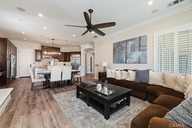 living room with ceiling fan, recessed lighting, wood finished floors, crown molding, and a chandelier