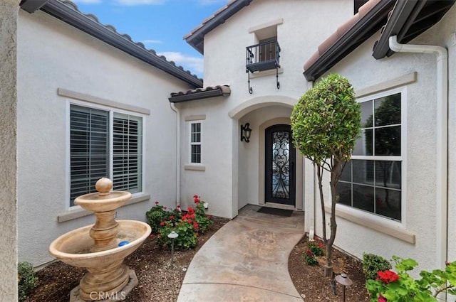 doorway to property with a balcony and stucco siding