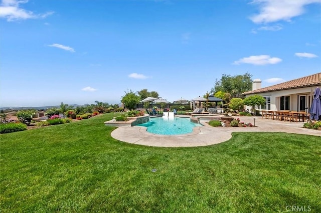 swimming pool with a patio area and a yard