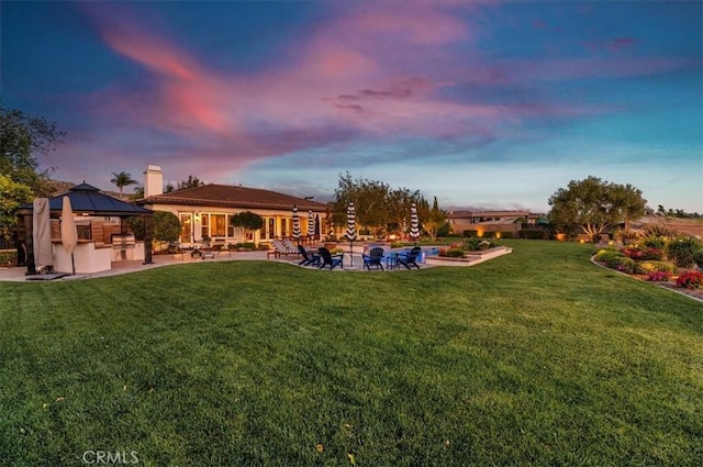 back of house at dusk featuring a gazebo, a patio, a yard, and a swimming pool