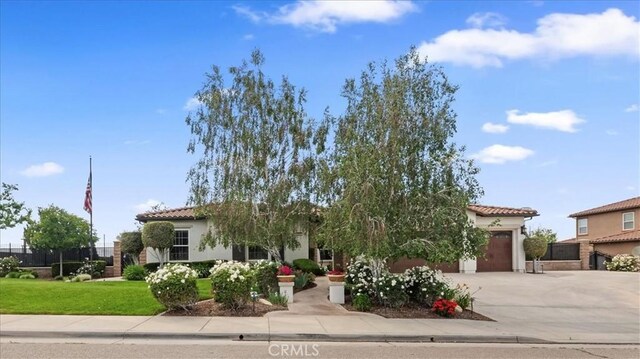 mediterranean / spanish-style house featuring an attached garage, a tile roof, concrete driveway, stucco siding, and a front lawn