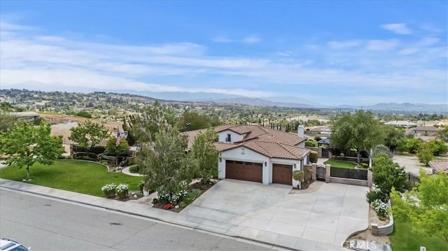 mediterranean / spanish home featuring a garage, a tiled roof, driveway, a mountain view, and stucco siding