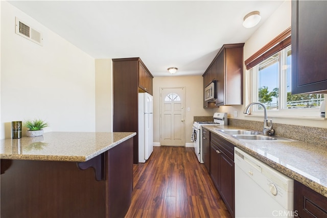 kitchen featuring white appliances, a sink, dark wood finished floors, and plenty of natural light