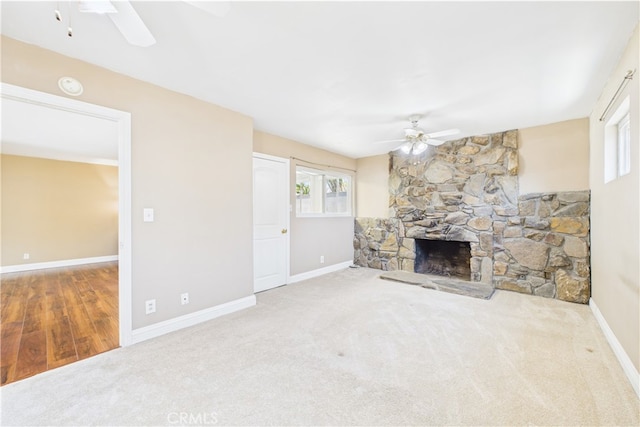 unfurnished living room featuring a ceiling fan, carpet floors, a fireplace, and baseboards