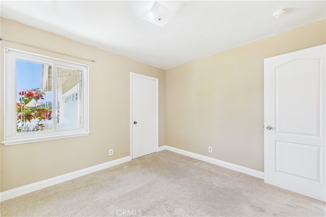 carpeted spare room featuring a smoke detector and baseboards