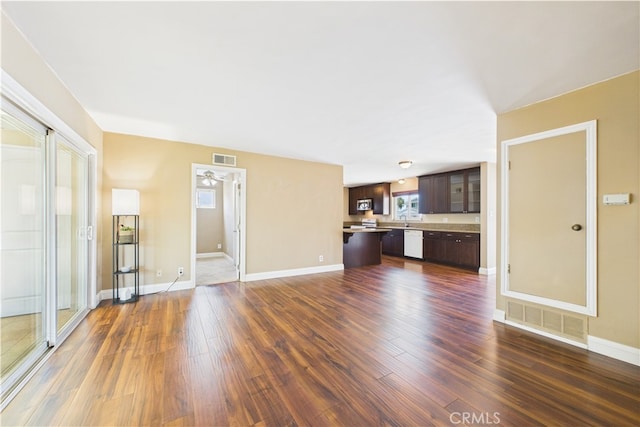 unfurnished living room featuring dark wood-style flooring, baseboards, and ceiling fan