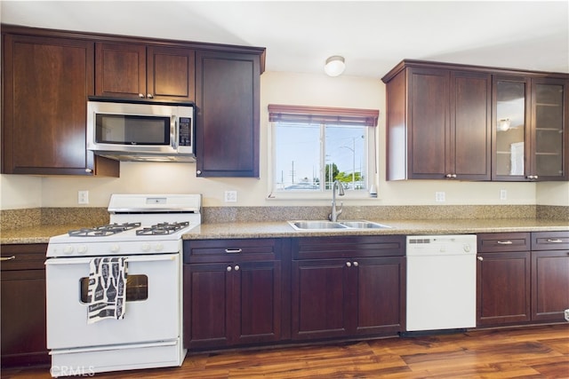 kitchen with white appliances, a sink, dark wood-style floors, glass insert cabinets, and dark brown cabinets