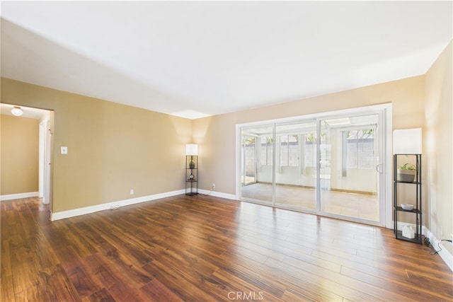 unfurnished room featuring dark wood-type flooring and baseboards