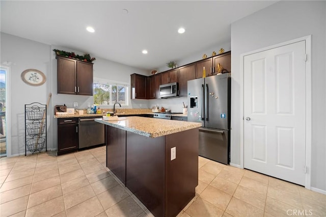 3344 Pokeroot Ln, San Bernardino, CA 92407 - kitchen with appliances with stainless steel finishes, dark brown cabinetry, a center island, light stone counters, and light tile patterned floors