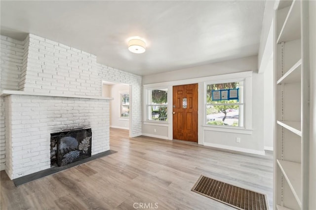 entryway with a brick fireplace, wood finished floors, and baseboards