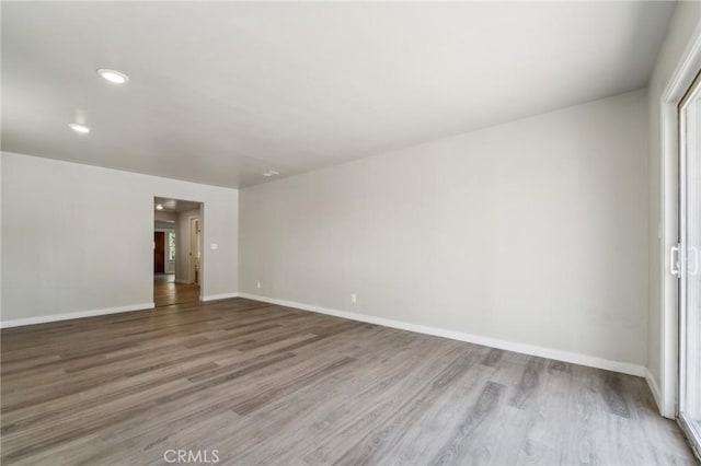 spare room with wood finished floors, baseboards, and recessed lighting