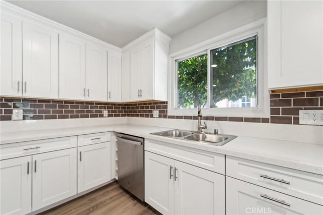 kitchen featuring stainless steel dishwasher, a sink, light countertops, white cabinetry, and decorative backsplash