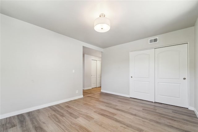 unfurnished bedroom featuring light wood-style flooring, baseboards, and a closet