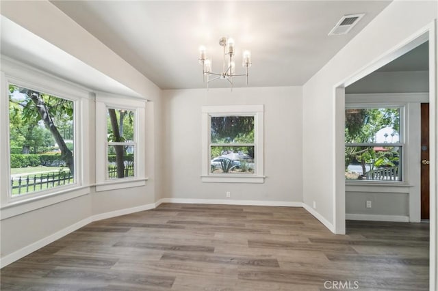 unfurnished dining area featuring a chandelier, wood finished floors, and baseboards