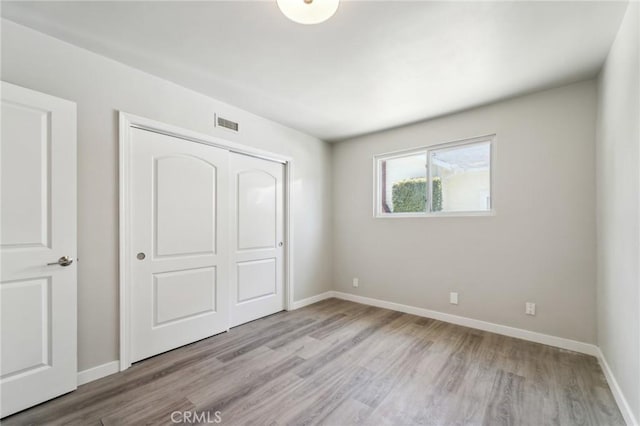 unfurnished bedroom with light wood-type flooring, a closet, and baseboards