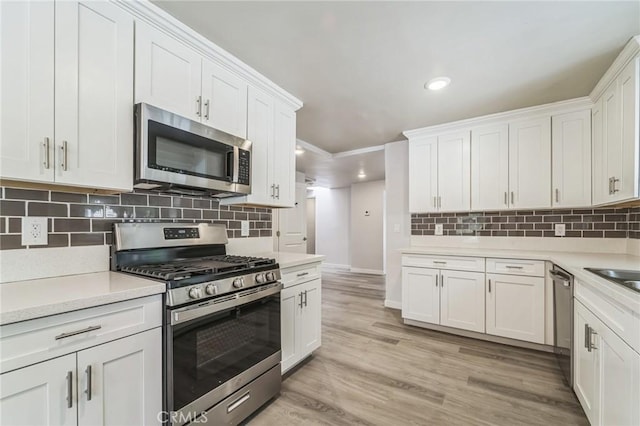 kitchen featuring stainless steel appliances, white cabinets, light countertops, recessed lighting, and backsplash