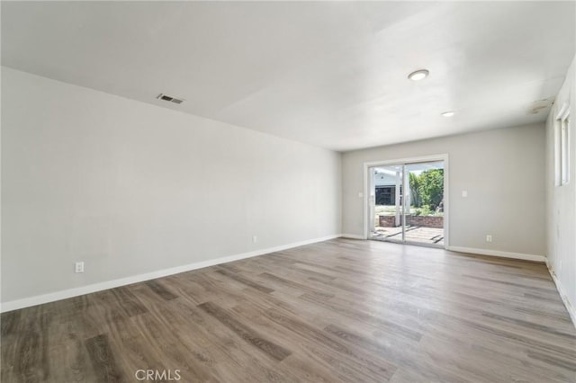 spare room with wood finished floors, baseboards, and recessed lighting