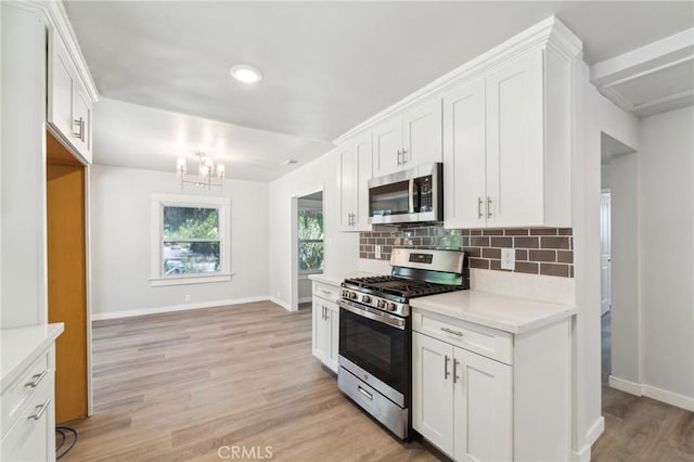 kitchen with appliances with stainless steel finishes, a chandelier, baseboards, and decorative backsplash