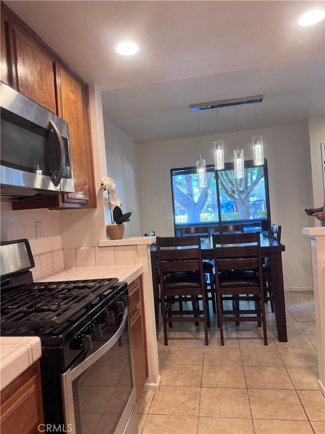 2364 S Cutty Way Unit 3, Anaheim, CA 92802 - kitchen with appliances with stainless steel finishes, tile countertops, recessed lighting, light tile patterned floors, and brown cabinetry