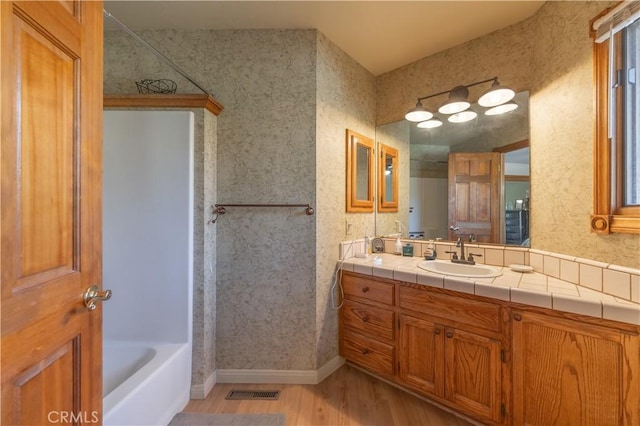 919 S Waldstrasse Way, Big Bear Lake, CA 92314 - bathroom with wood finished floors, vanity, wallpapered walls, and shower / bathtub combination