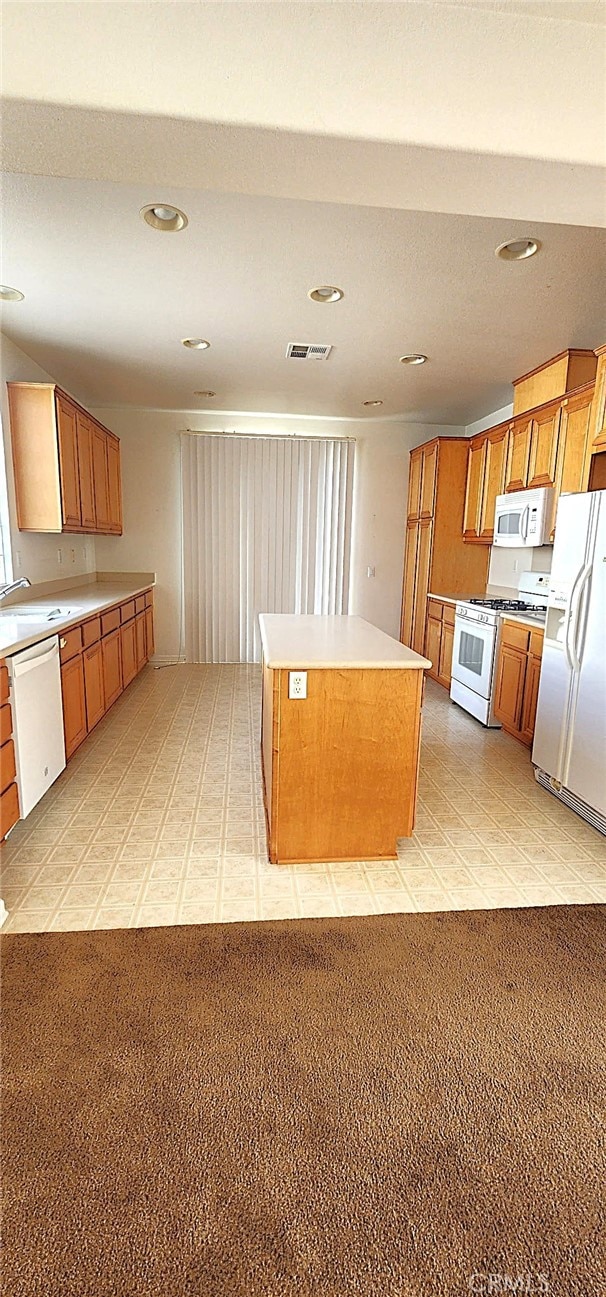 8281 Triplett Ln, Hemet, CA 92545 - kitchen with white appliances, a center island, a sink, recessed lighting, and brown cabinets