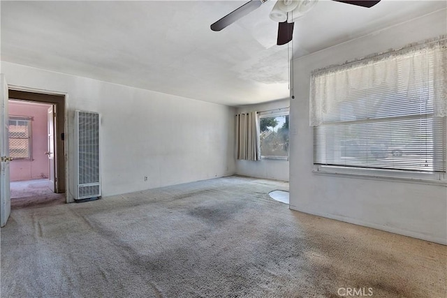 carpeted empty room featuring a heating unit and a ceiling fan