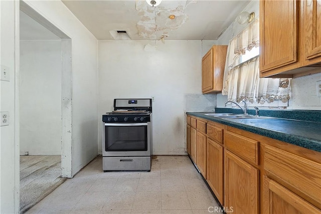 kitchen featuring stainless steel gas stove, a sink, dark countertops, and brown cabinetry