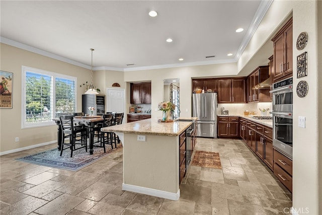 kitchen featuring stainless steel appliances, stone tile floors, baseboards, crown molding, and a center island